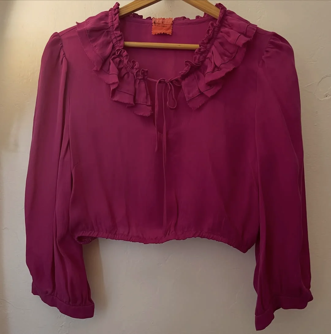 Magenta silk ruffle blouse on a hanger